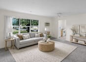 Thumbnail 15 of 36 - A living room with a grey couch, a round wicker table, and a grey rug.