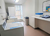 Thumbnail 21 of 58 - A medical office with a white cabinet, a blue towel, and a poster on the wall.