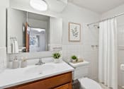 Thumbnail 58 of 58 - A white bathroom with a wooden vanity and a white toilet.