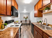 Thumbnail 54 of 58 - A kitchen with brown cabinets and a black stove top.