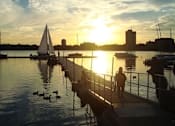 Thumbnail 22 of 36 - A serene sunset view at a marina with people enjoying the view.