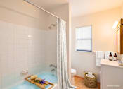 Thumbnail 14 of 36 - A bathroom with a shower curtain and a bathtub filled with blue water.