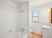 Thumbnail 13 of 36 - A white bathroom with a tub, toilet, and sink.