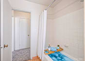 Thumbnail 19 of 36 - A bathroom with a white tub and a white shower curtain.