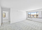 Thumbnail 9 of 36 - A large, empty room with a carpeted floor and a window showing a view of a street.