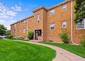 Thumbnail 2 of 36 - A brick building with a green lawn in front.