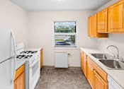 Thumbnail 25 of 36 - A kitchen with a white fridge, white stove, and a window with a view of the street.