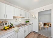 Thumbnail 18 of 36 - A kitchen with white cabinets and a wooden cutting board with lemons and herbs on it.