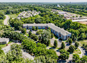 Thumbnail 5 of 59 - A large building surrounded by trees is the main focus of this aerial image.