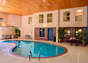 Thumbnail 58 of 59 - A large indoor swimming pool with a wooden ceiling and a blue door.