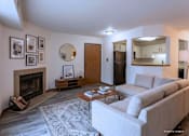 Thumbnail 48 of 59 - A living room with a grey couch, a fireplace, and a coffee table.