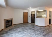 Thumbnail 49 of 59 - A living room with a fireplace and a kitchen area in the background.