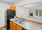 Thumbnail 47 of 59 - A kitchen with a black fridge and a marble countertop.
