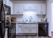 Thumbnail 26 of 59 - A kitchen with white cabinets and a black refrigerator.