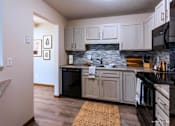Thumbnail 29 of 59 - A kitchen with a black fridge and stove top oven.