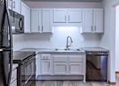 Thumbnail 27 of 59 - A kitchen with white cabinets and black appliances.
