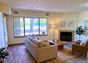 Thumbnail 44 of 59 - A living room with a couch, a fireplace, and a large window.