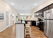Thumbnail 6 of 19 - A kitchen with a white island and stainless steel appliances.