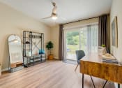 Thumbnail 7 of 11 - a living room with a desk and a sliding glass door