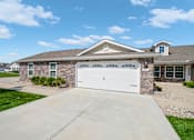 Thumbnail 1 of 15 - A house with a white garage door and a stone wall.