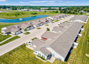 Thumbnail 7 of 15 - A large building with a grey roof is surrounded by smaller buildings and a body of water.