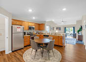 Thumbnail 6 of 15 - A kitchen with a table and chairs in the middle of the room.