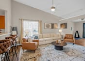 Thumbnail 9 of 15 - A living room with a white couch, brown chairs, and a rug.