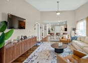 Thumbnail 5 of 15 - A living room with a large couch, a coffee table, and a television mounted on the wall.