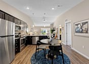 Thumbnail 7 of 20 - A modern kitchen with a dining table and chairs.