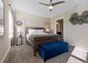 Thumbnail 11 of 20 - A bedroom with a bed, a bench, and a ceiling fan.
