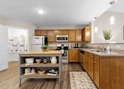 Thumbnail 17 of 21 - A kitchen with wooden cabinets and a grey island.