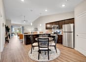 Thumbnail 9 of 23 - A modern kitchen with a dining table and chairs in the middle.