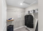 Thumbnail 18 of 23 - A walk-in closet with a black coat hanging on a hanger.