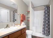 Thumbnail 11 of 15 - A bathroom with a white toilet, sink, and shower.
