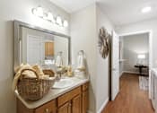 Thumbnail 13 of 15 - A bathroom with a mirror, sink, and a basket of towels.