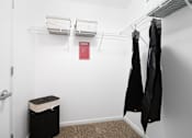 Thumbnail 12 of 15 - A small closet with a red sign on the wall and two coats hanging up.