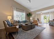 Thumbnail 10 of 20 - A living room with a brown leather chair and a grey sofa with blue and white pillows.