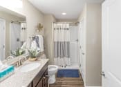 Thumbnail 12 of 18 - A bathroom with a white toilet, sink, and shower curtain.