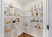 Thumbnail 7 of 18 - A pantry with a white door and shelves filled with jars and containers.