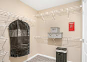 Thumbnail 13 of 18 - A walk-in closet with a black coat hanging on a rod.