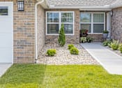 Thumbnail 3 of 18 - A house with a white garage door and a small garden in front.