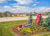 Thumbnail 4 of 16 - A Redfin sign is in front of a landscaped area with a flag.