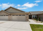 Thumbnail 1 of 16 - A house with a grey garage door and a stone pillar.