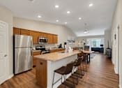 Thumbnail 6 of 16 - A kitchen with a refrigerator, stove, and bar area.