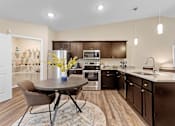 Thumbnail 4 of 18 - A kitchen with brown cabinets and a round table with chairs.