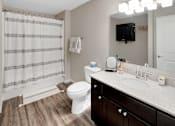 Thumbnail 17 of 18 - A bathroom with a white toilet, a sink, and a shower curtain.