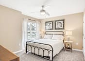 Thumbnail 16 of 18 - A bedroom with a bed, nightstand, and a ceiling fan.