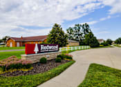 Thumbnail 4 of 20 - The image shows a sign for Redwood Apartment Homes in front of a building.