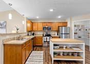 Thumbnail 5 of 20 - A kitchen with wooden cabinets and a stainless steel refrigerator.
