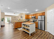 Thumbnail 9 of 20 - A kitchen with wooden floors and a white island.